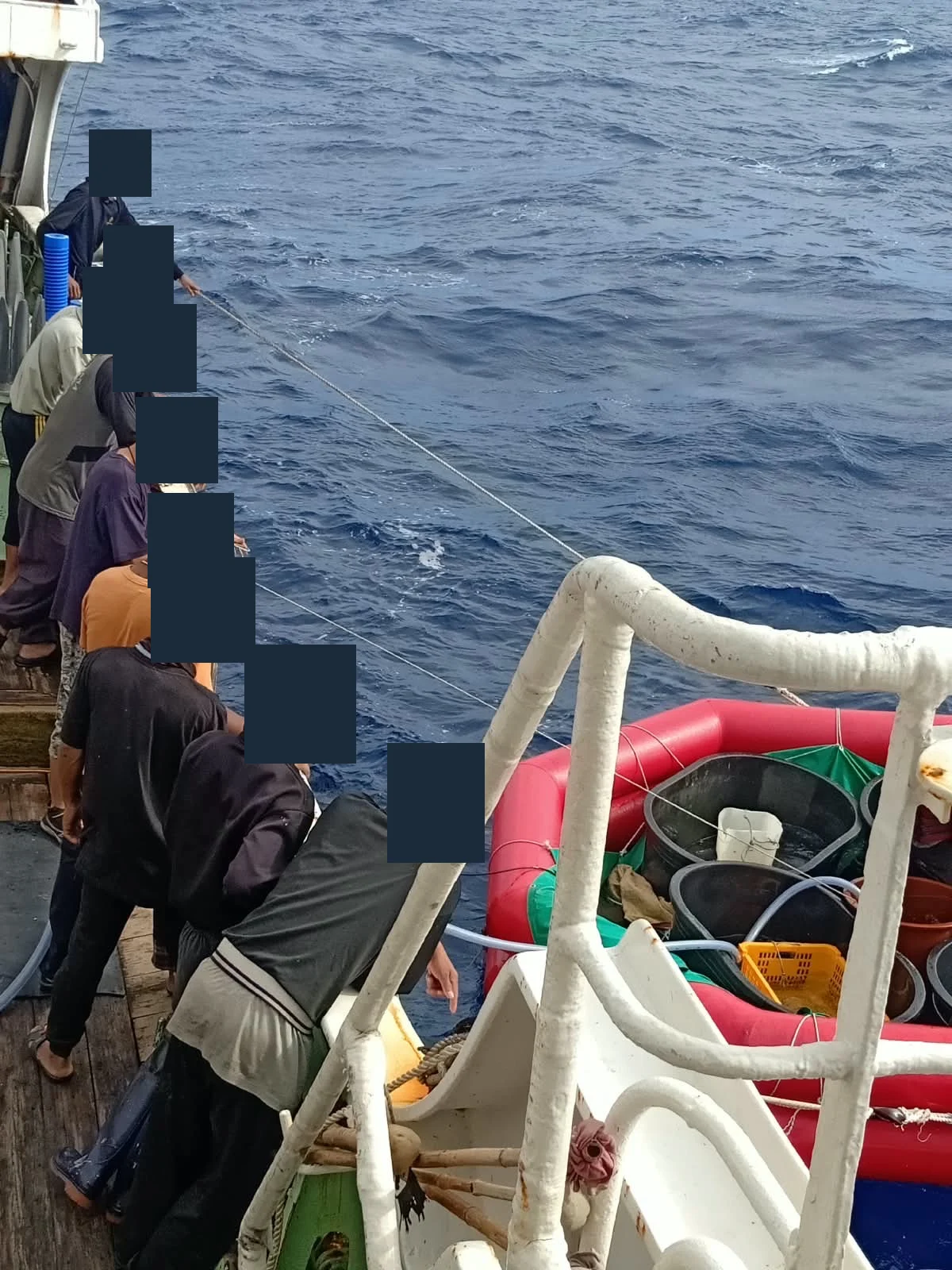 Awak di pagar kapal menarik tali perahu karet